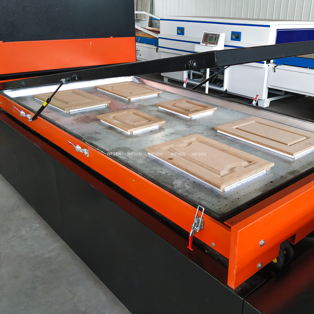 Six raised panel MDF doors loaded on the worktable of a WFSEN vacuum membrane press before the membrane frame closes