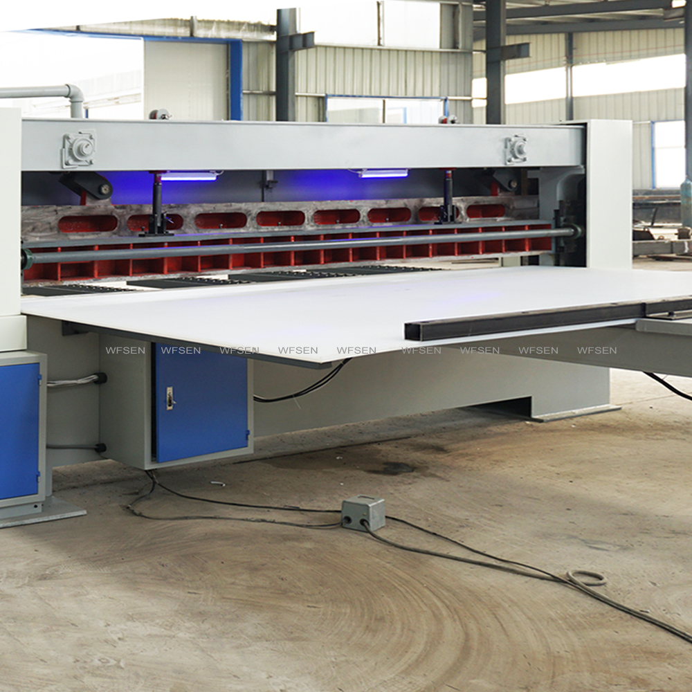 Knife beam, hold-down bar and worktable of a WFSEN veneer clipper, with the foot pedal on the floor beneath the table